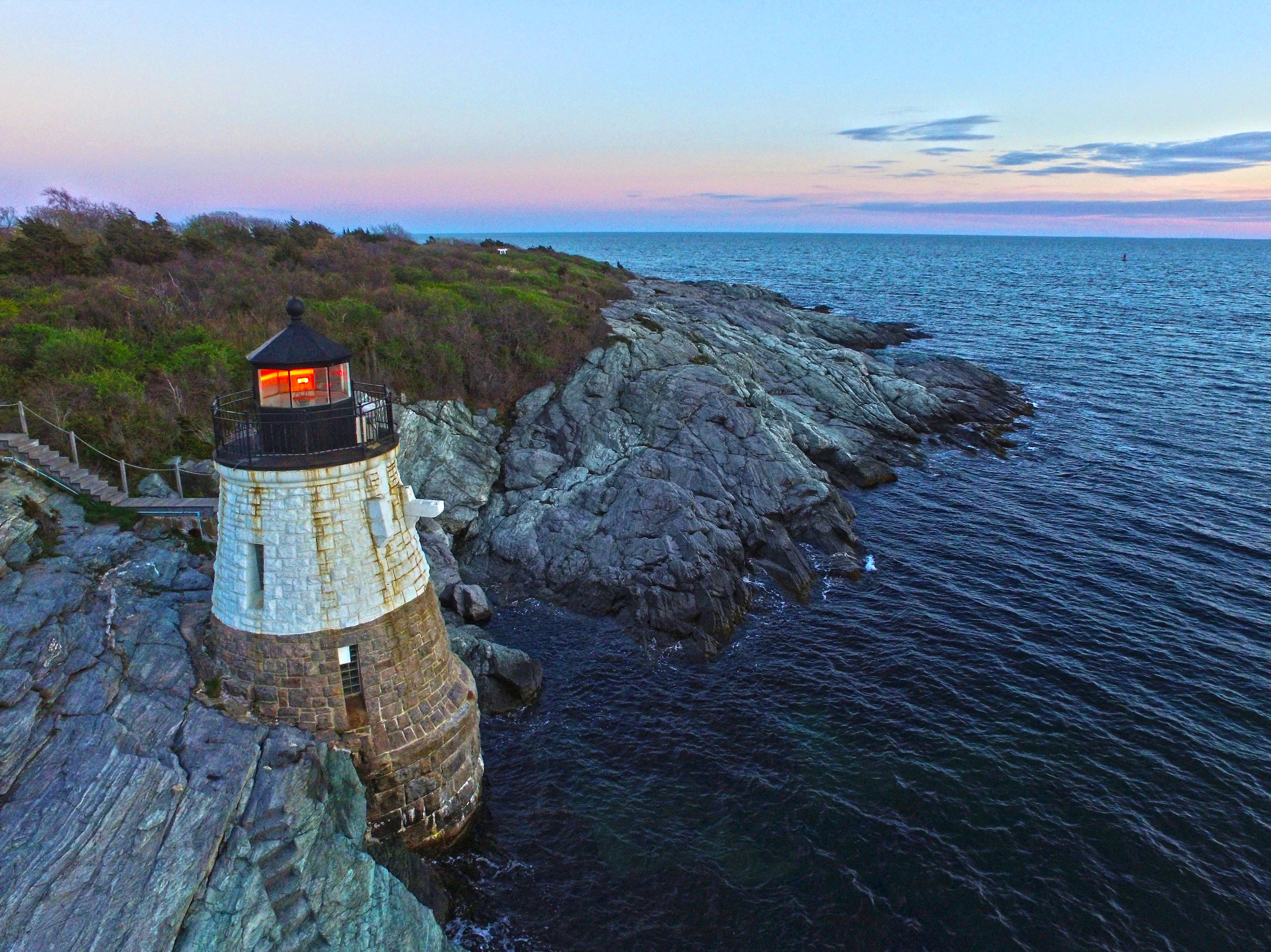 a drone shot of a lighthouse on the water