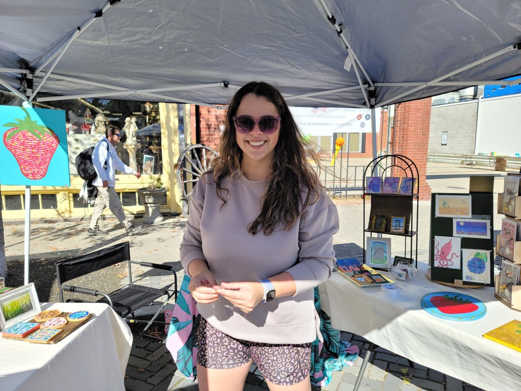 a photo of nina smiling in front of her craft booth